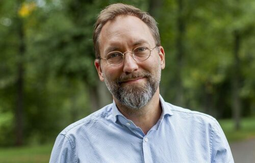 Porträttfoto av Olle Forshed, leendes mot kameran med träd i bakgrunden.