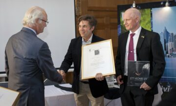 Magnus Lundgren och Staffan Widstrand tar emot ett pris av kung Carl XVI Gustaf. En av pristagarna skakar hand med kungen och håller i ett inramat diplom, medan den andra pristagaren håller i en bok med titeln "Ett vildare liv".