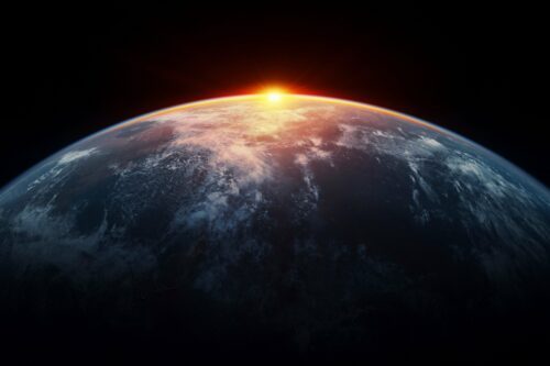 Jordens krök sett från rymden vid soluppgång, glödande atmosfär och moln över mörka oceaner.