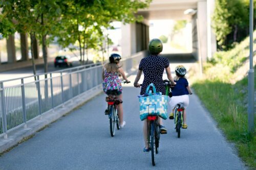 uppsala-satsar-p-c.jpg Vuxen och två barn cyklar på cykelväg med ryggen mot kameran.