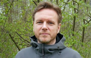 Porträttfoto av Mattias de Woul, med skog i bakgrunden.