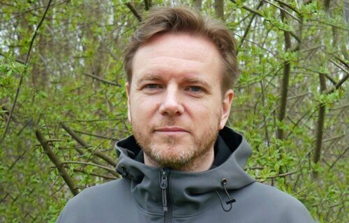 Porträttfoto av Mattias de Woul, med skog i bakgrunden.