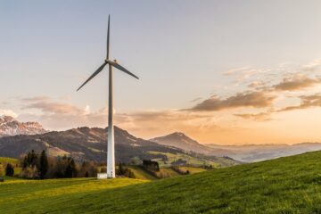 alternative-energy-clouds-efficiency-Nordea A wind mill stands in a field with mountains in the background
