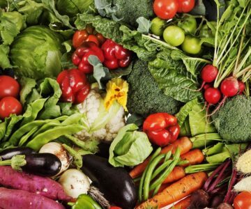 Bild ovanifrån på många grönsaker tätt intill varandra; blomkål, broccoli, aubergine, morötter, paprikor, tomater, lök och andra grönsaker.