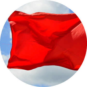 Rund bild: Röd flagga vajar i vinden mot en blå himmel med moln.