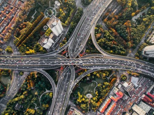 drönarbild av flera motorvägar som korsar, med flera byggnader runtomkring.