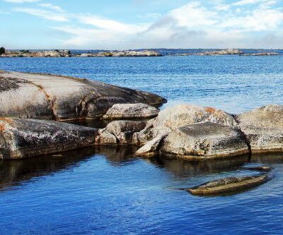 skärgården, blått vatten och klarblå himmel med några moln samt klippor syns.