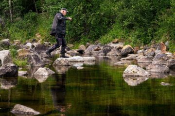 En man balanserar på stenar över en bäck