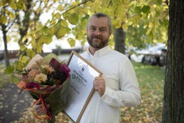 Porträttfoto av Emil Nilsson, som håller en blombukett och ett diplom.