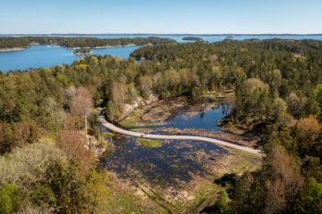 Vattensamling omgiven av skog, fotad från luften.