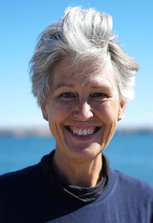 Porträttfoto av Angela Wulff, kort vitt hår och stort leende med blicken in i kameran.