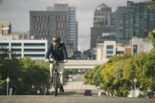 En man cyklar på en bilväg i storstadsmiljö