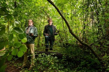 Minh-Xuan truong och René van der Wal står i en tjock skog och håller i mobiltelefoner och tittar sig omkring.