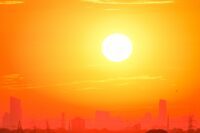 Varm stad Gul och orange bild, en gul sol på orange himmel ovanför konturen av en stad.